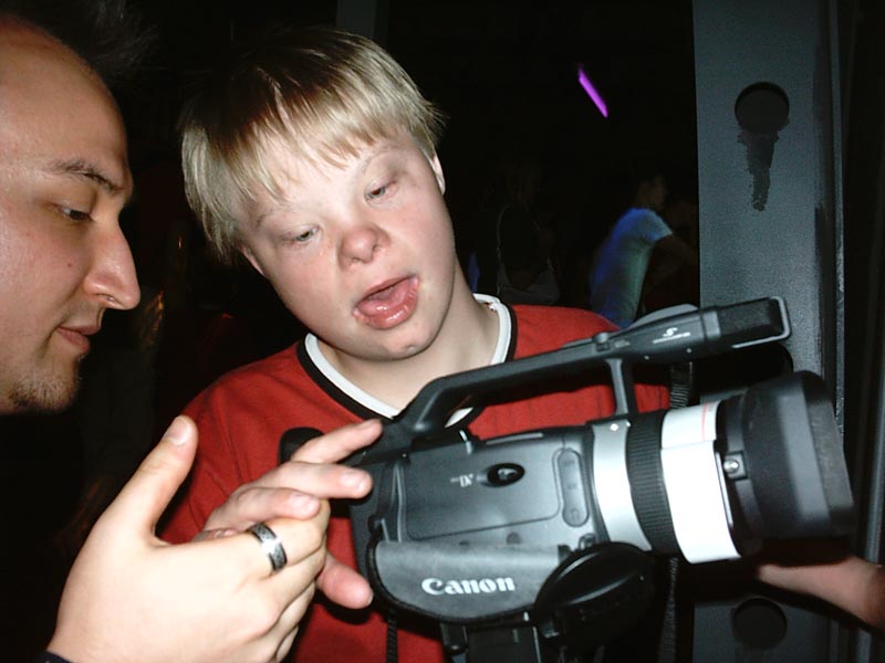 Projekt "Weltansichten - Medienprojekt mit behinderten Kindern und Jugendlichen". Ein junger Mann und ein Kind betrachten eine Filmkamera.