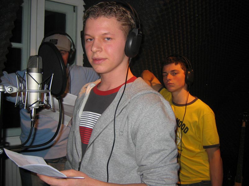 Projekt "Radio Sloschnaja Kompanija". In einem Tonstudio stehen drei Jugendliche mit Kopfhörern. Einer von ihnen steht vor dem Mikrofon.