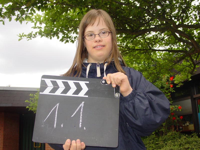 Projekt "ausdrucksstark - Modellprojekte zur Medienarbeit mit Heranwachsenden mit Behinderung". Ein junges Mädchen hält eine Filmklappe in den Händen.
