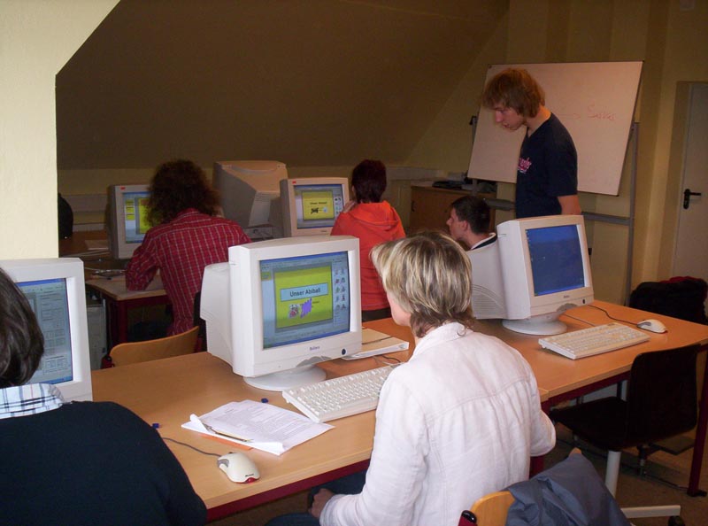 Projekt "Teach your teacher". In einem Computerraum sitzen mehrere junge Erwachsene vor den Computerbildschirmen.