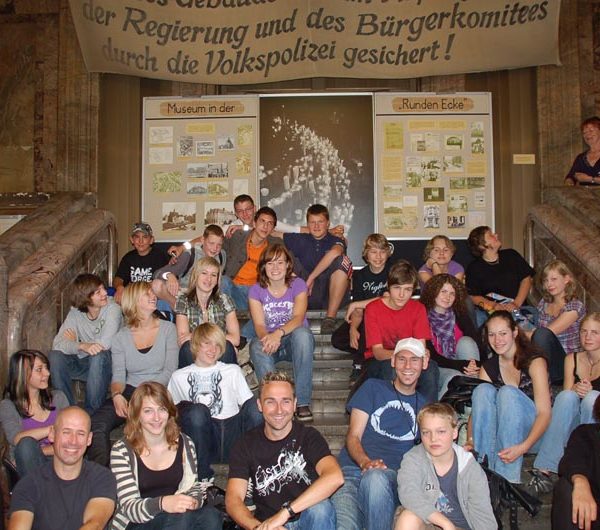 Projekt "Mediencamp 20 Jahre Mauerfall". Gruppenfoto der Teilnehmenden, welche verteilt auf einer Treppe sitzen.
