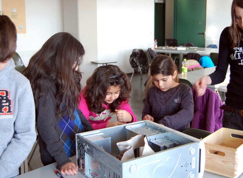 Projekt "Das Paderborner Recycling-PC-Projekt für benachteiligte Kinder und Jugendliche". Vor einem geöffneten Computergehäuse stehen drei Mädchen und betrachten dessen Innenleben.