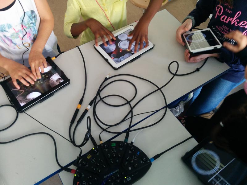 Projekt "app2music - Appmusik-AGs in Berliner Schulen". Foto von drei Tablets, die jeweils die Rolle eines Musikinstruments einnehmen und miteinander verbunden sind.