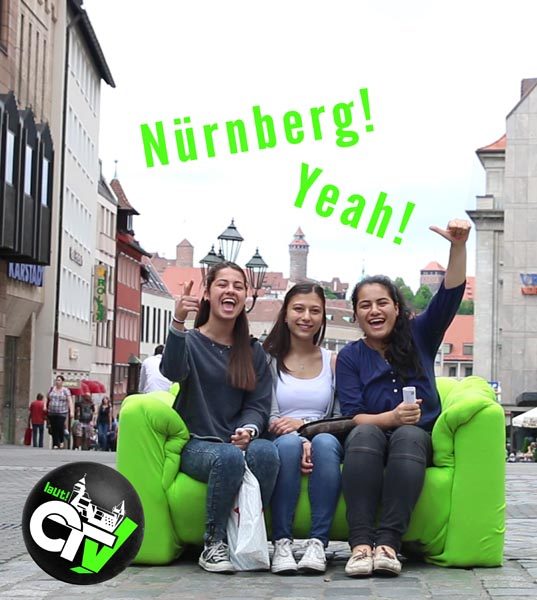 Projekt "Laut! CiTyVee - Ein Nürnberger YouTube-Kanal". Drei junge Frauen sitzen in einer Stadt auf einem grünen Sofa.