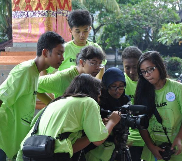 Projekt "EinBlick - der interkulturelle Filmaustausch". Foto einer Gruppe Jugendlicher, die alle das gleiche T-Shirt tragen und eine Kamera betrachten.