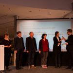 Dieter Baacke Preisverleihung 2017: Der Moderator steht mit den Mitwirkenden des Projekts "Smarte Regeln statt Verbote: "Smart"phone Projekte" auf der Bühne.