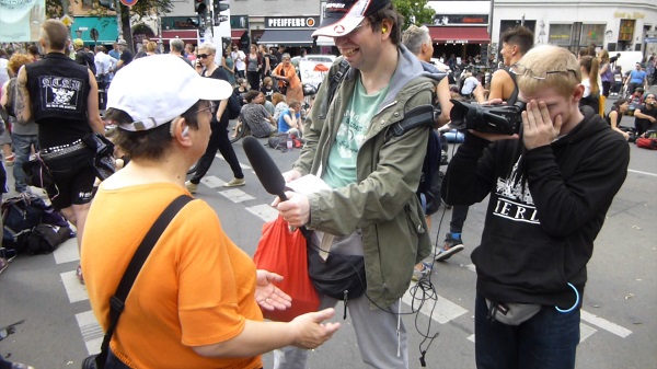Projekt "Wahl inklusiv - Menschen mit und ohne Behinderungen machen Filme". Zwei junge Erwachsene sind mit Kamera und Mikrofon ausgestattet und filmen eine weitere.