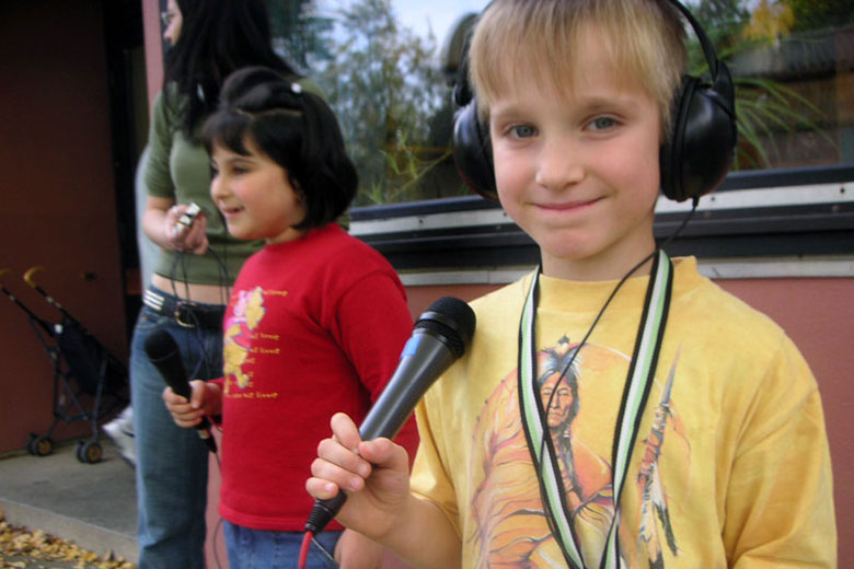 Foto von zwei Kindern, die mit Mikrofonen und Kopfhörern ausgestattet sind.