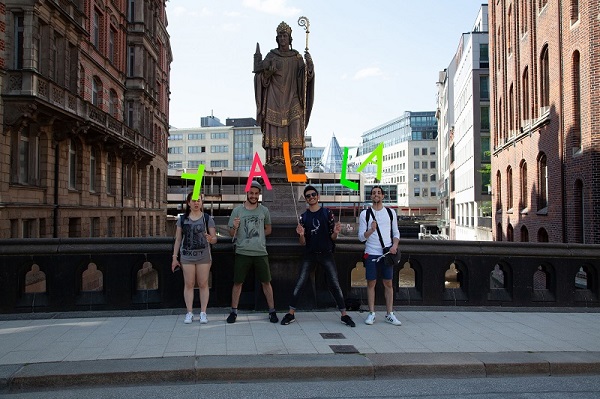Vier Jugendlich stehen in Hamburg vor der Statue des Bischofs Ansgar und halten Buchstaben in die Höhe, die das Wort "Yalla" ergeben.