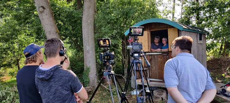 Kamerateam filmt einen Mann und eine Frau, die in einem Gartenhaus stehen